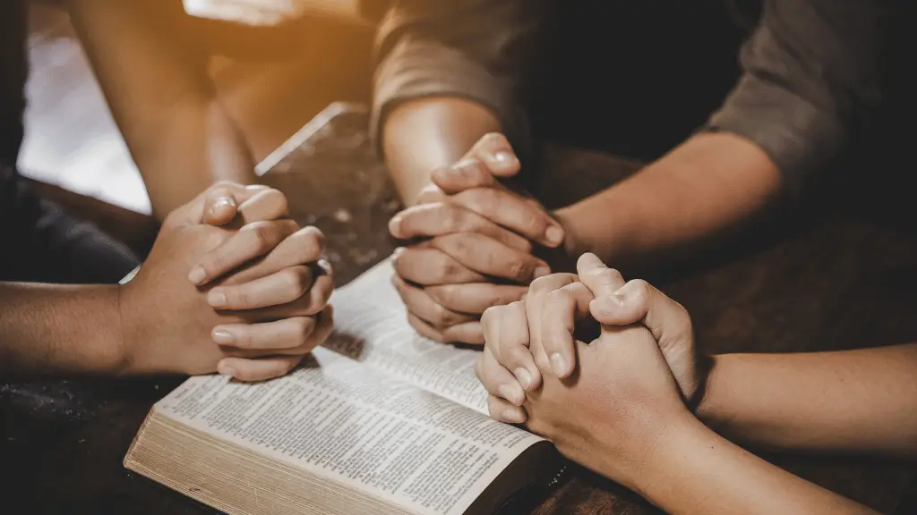 Mãos em oração com Bíblia aberta