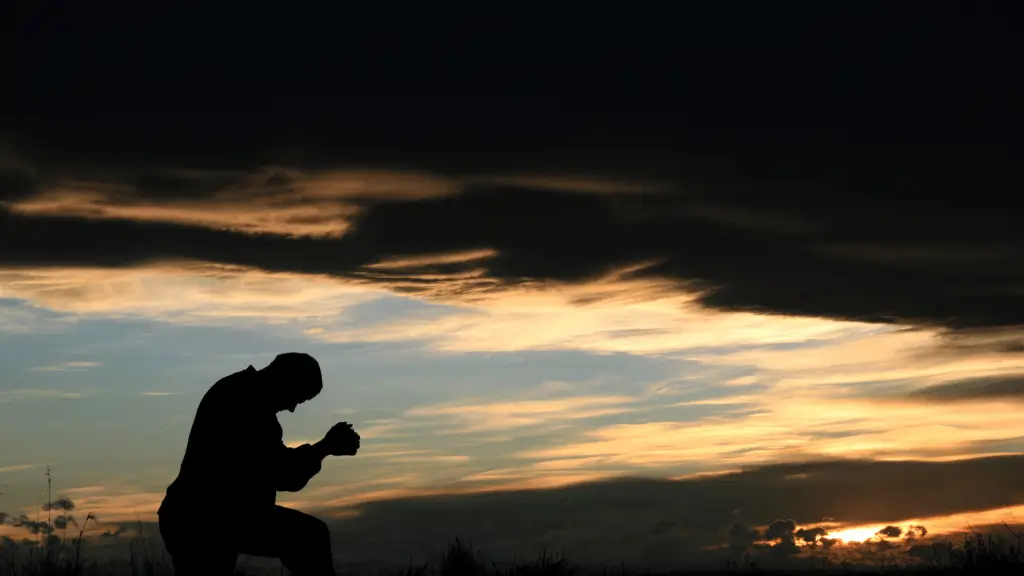 Homem ajoelhado em oração ao entardecer com céu dramático e nuvens douradas ao fundo